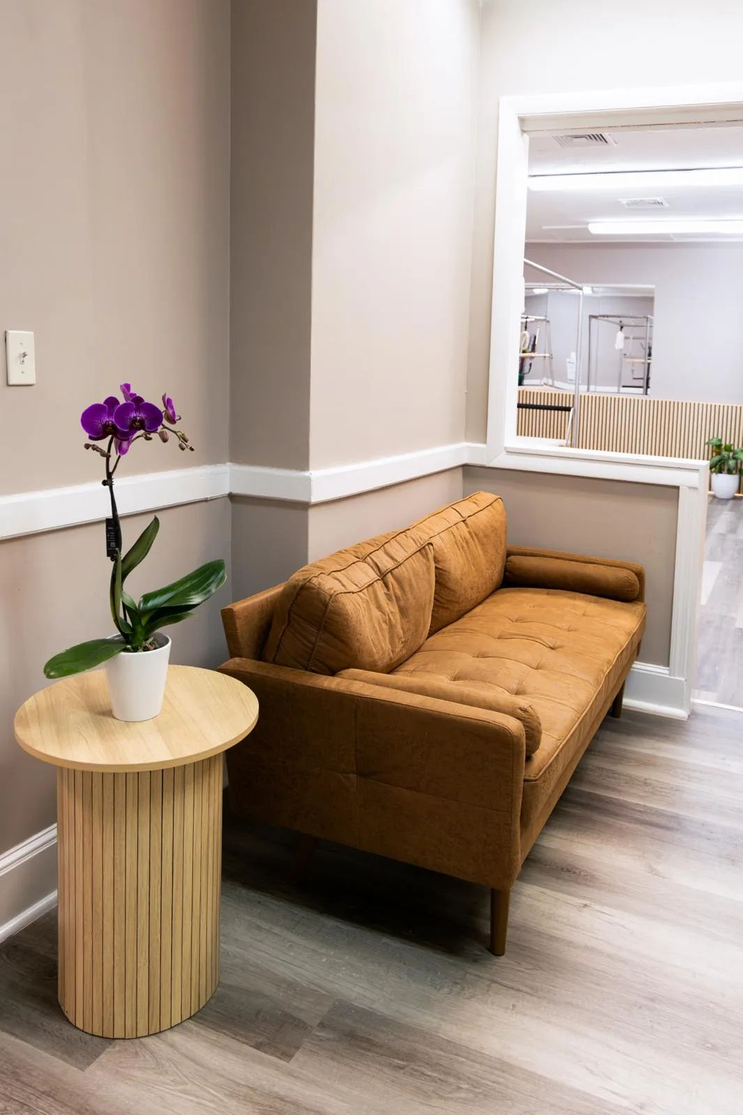 Cozy waiting area with a leather sofa and an orchid at Inspire Pilates Studio
