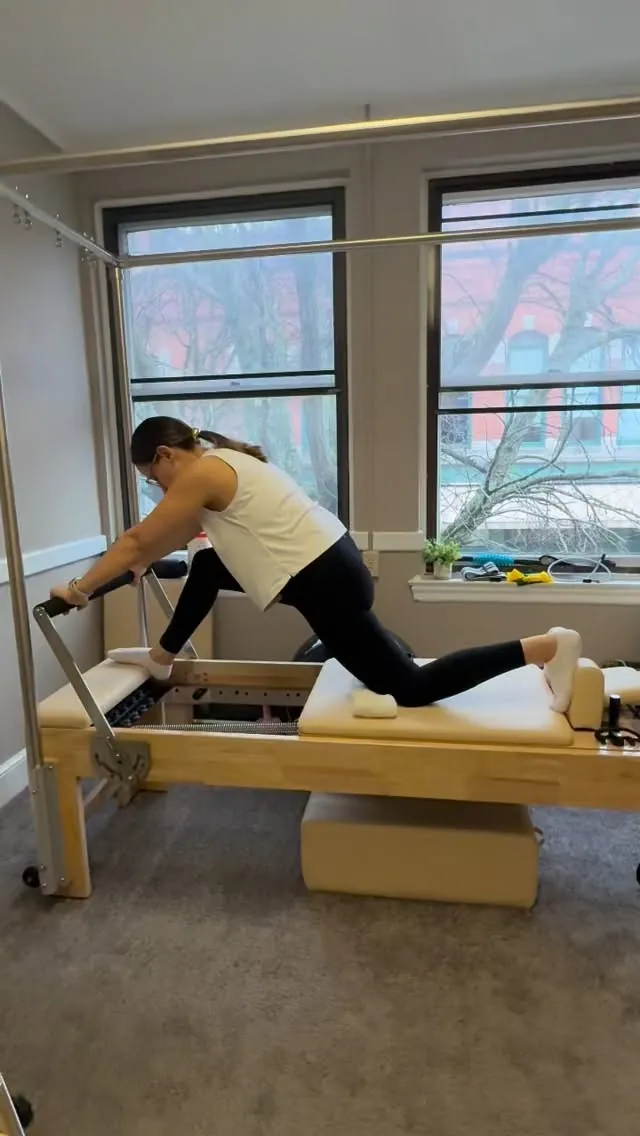 Client doing a lunge on the Reformer during a private Pilates session in Lowell, MA