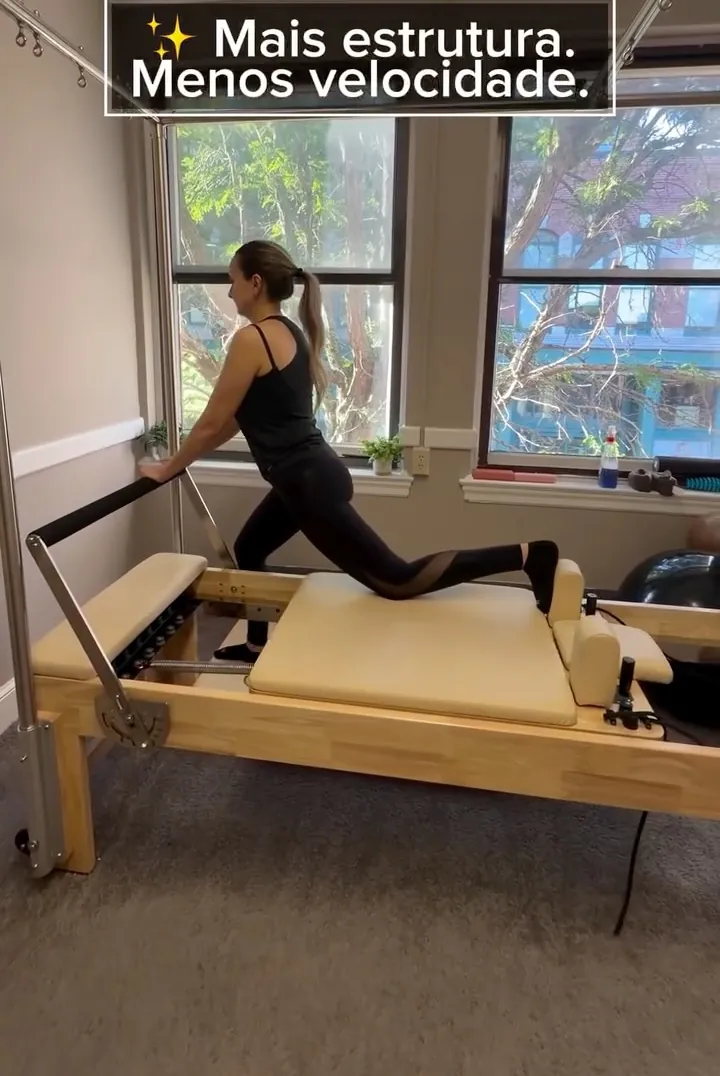 Pilates instructor guiding a client through a split stretch on the Reformer during a private session