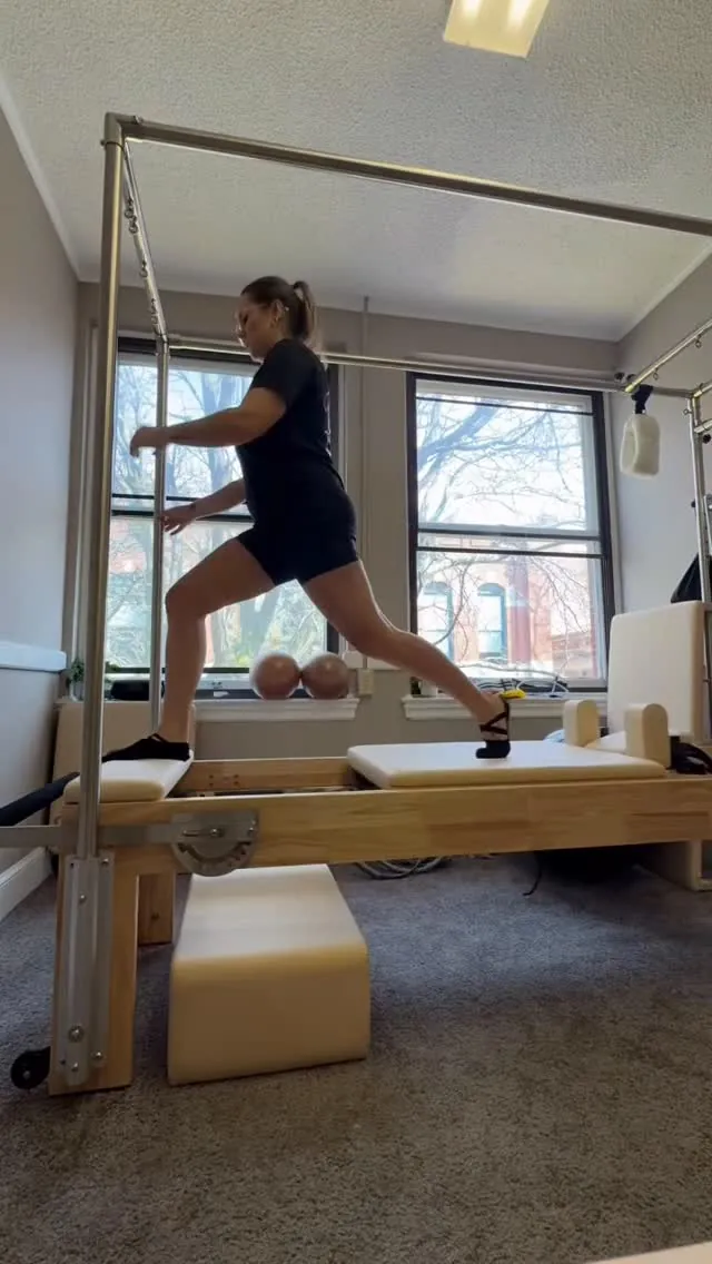 Client doing a standing balance exercise on the Reformer in a Pilates studio