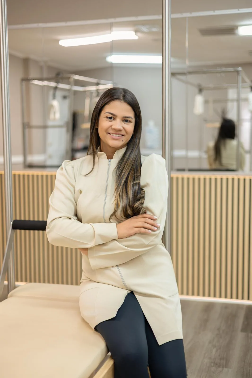 Bruna Felix Costa, owner and Pilates instructor, smiling next to a Cadillac in her studio